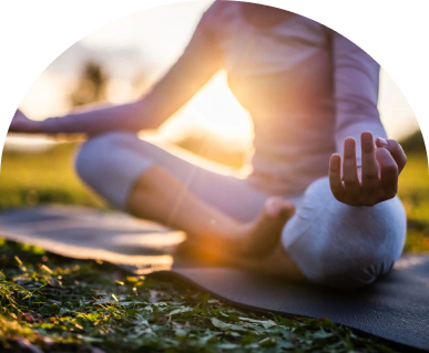 Person meditating outdoors at sunset.