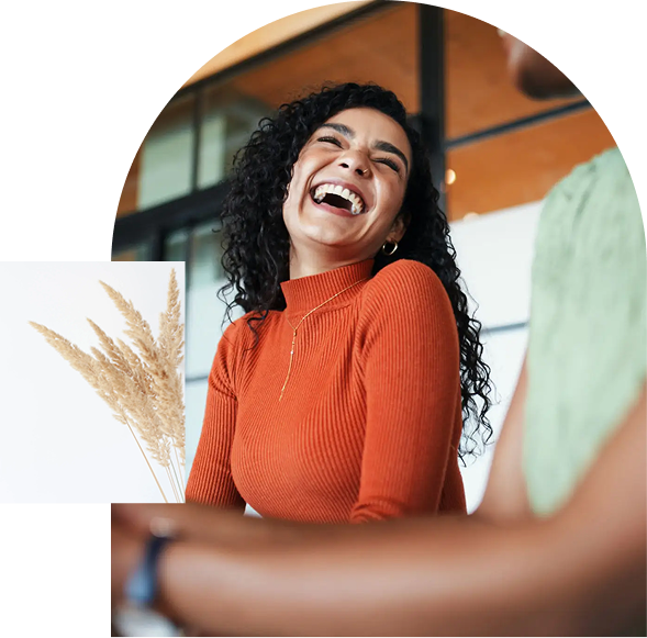 Woman laughing in orange sweater indoors.
