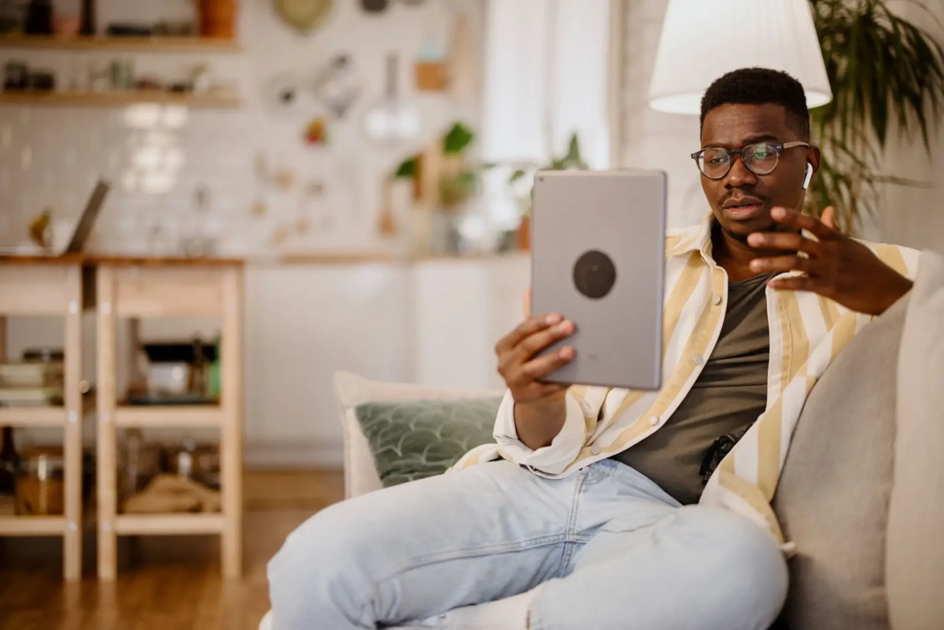 Man video chatting on tablet in living room.